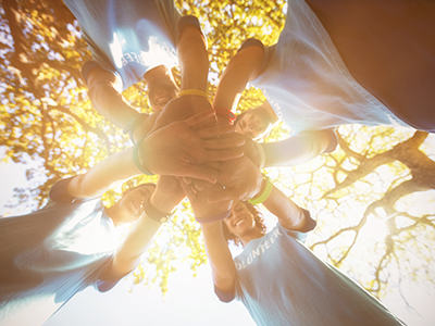 Volunteers forming a hand stack, photographed from below.. Link to Volunteering Fair – February 2025.