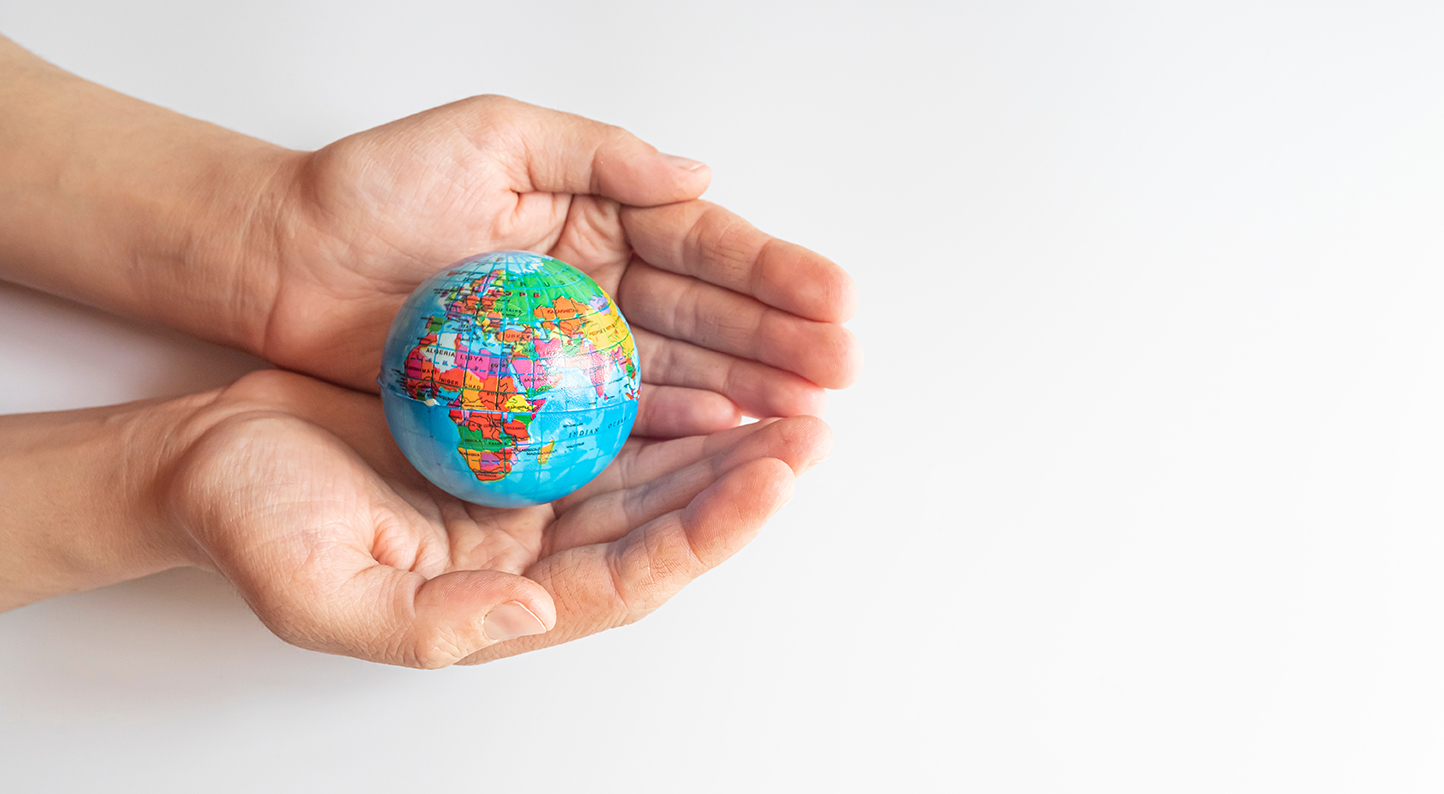 Cupped hands, palms upwards, holding a globe.