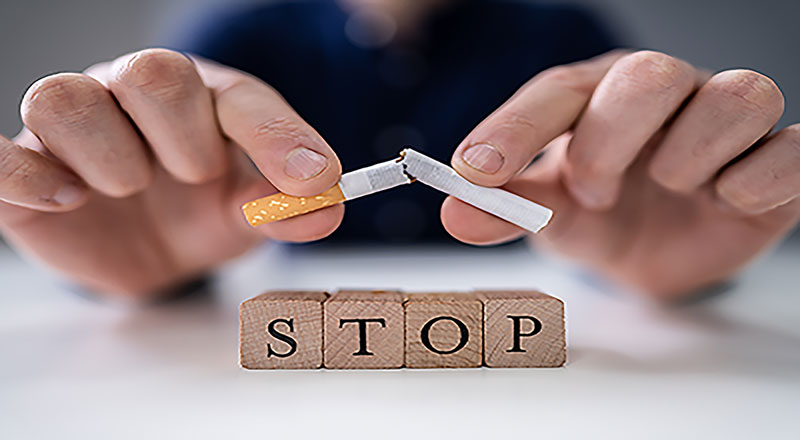 hands snapping a cigarette above a stop sign