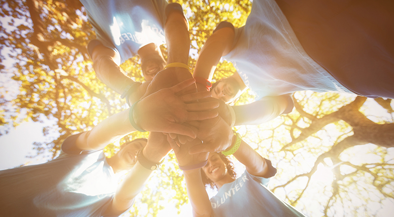 Volunteers forming a hand stack, photographed from below.